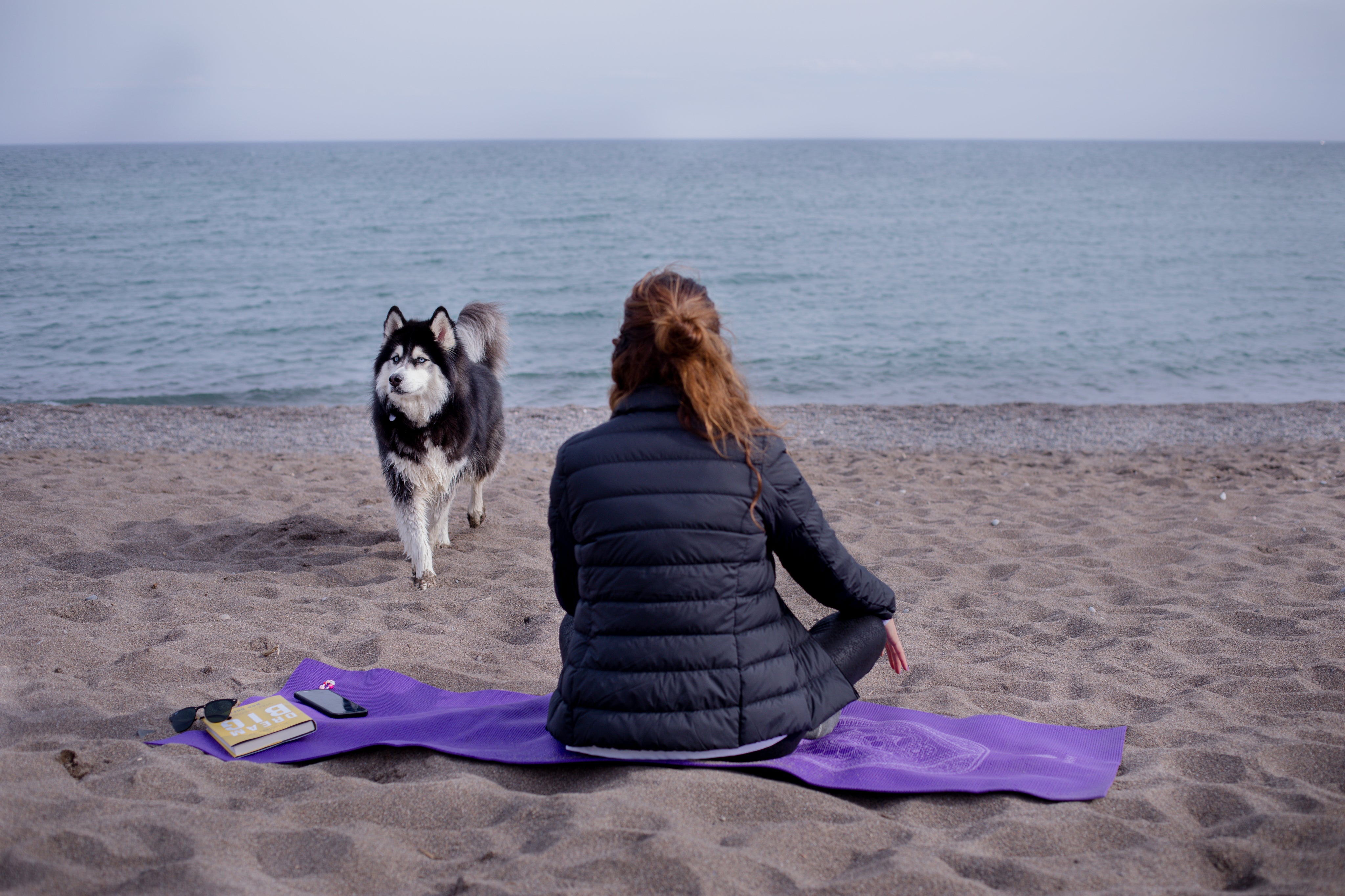 files/person-sits-on-a-mat-at-the-beach-and-looks-out-to-the-water.jpg